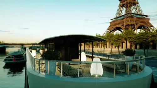 Curved deck of a floating venue on the Seine at dusk, with the Eiffel Tower framed in the background