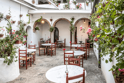 Whitewashed Andalusian patio with brick archways, potted flowers and café tables