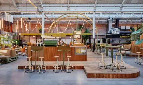 Industrial-chic restaurant and bar venue in Amsterdam with exposed brick walls, steel arch structures and raised wooden bar area, hosts up to 700 guests