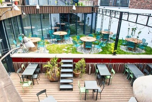 Aerial view of a two-level courtyard with wooden decking, cable-reel tables and a small lawn
