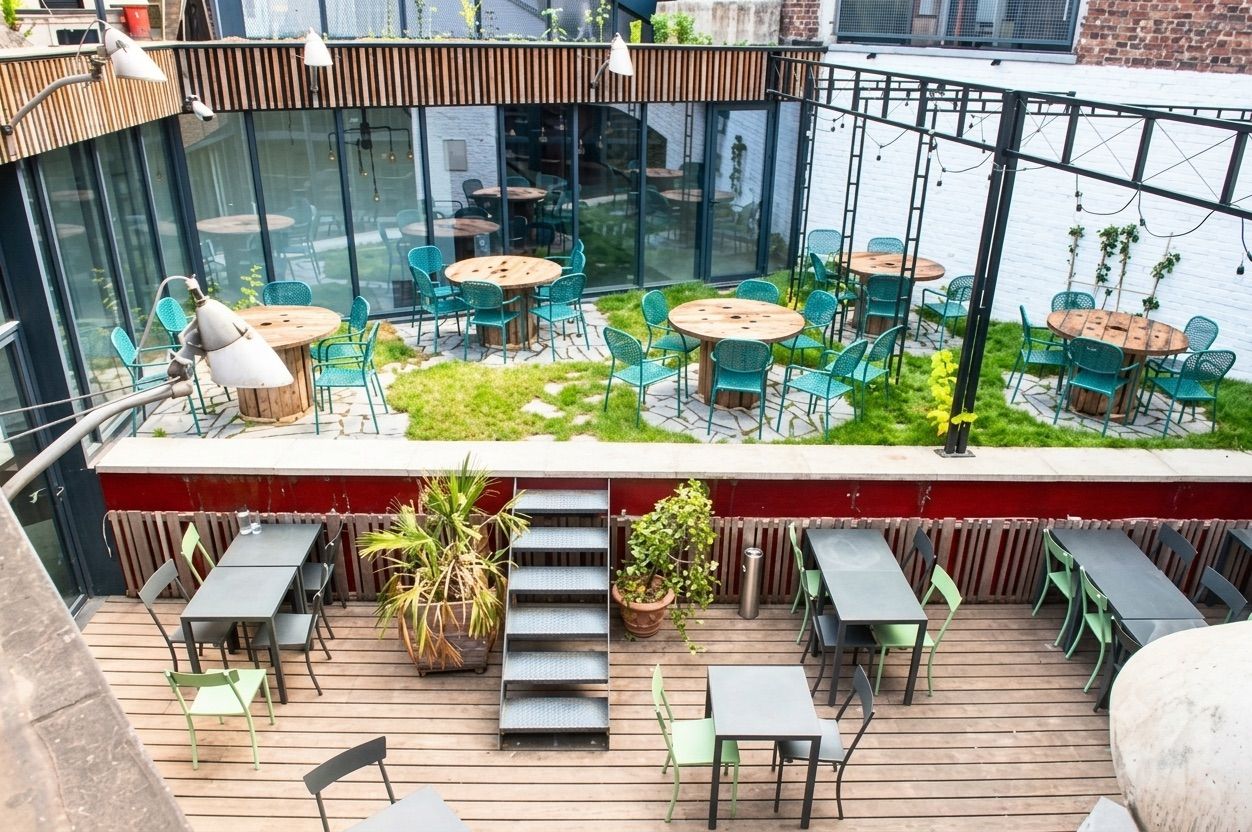 Industrial courtyard event venue in Brussels featuring a wooden deck, landscaped garden and flexible spaces for networking events and receptions.