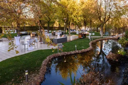 Lakeside garden venue near Madrid with cocktail tables, autumn trees and a pond, set up for exclusive corporate events on Eventflare