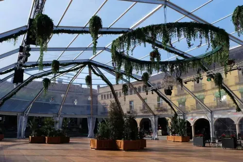 Transparent glass-domed pavilion in Barcelona with hanging greenery installations and surrounding historic archways, hosts up to 1,300 guests, 1,350 square metres