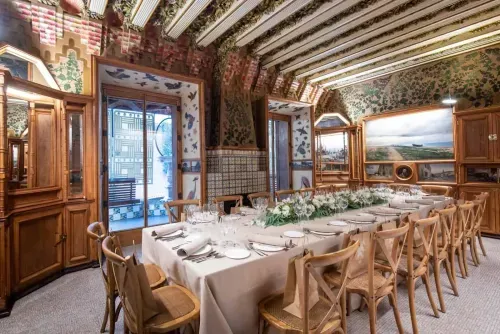 Antoni Gaudí architecture dining hall in Barcelona with painted vaulted ceilings, mosaic tiles and a long banquet table set for guests, hosts up to 180 guests