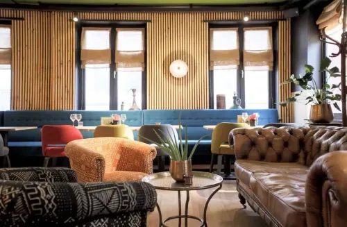 Lounge area with Afro-Mediterranean decor at a Brussels event venue, mixing leather sofas, patterned armchairs and slatted wood panelling.