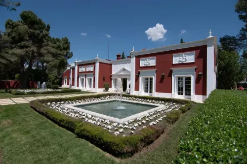 Neoclassical estate in Madrid with red and white facade, manicured hedge gardens and a formal fountain, hosts up to 400 guests
