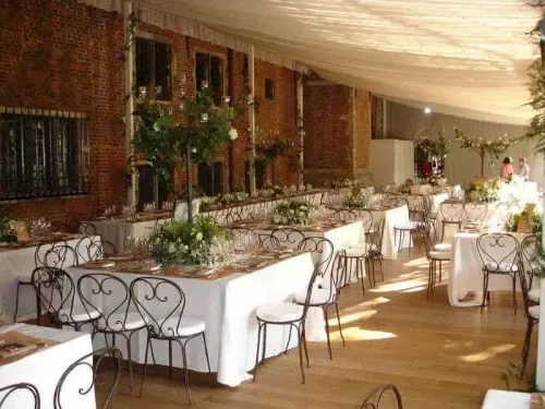 Marquee dining setup at a Flemish Renaissance estate near Brussels with exposed brick walls, long banquet tables and floral centrepieces