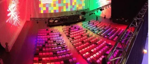 Conference auditorium in Brussels with tiered theatre seating and colourful triple-screen projection wrapping the stage, hosts up to 400 delegates