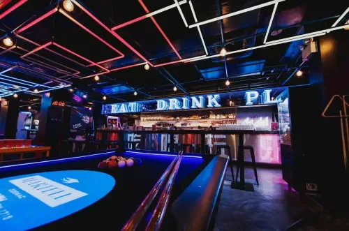 Retro arcade and live music venue in Singapore with neon lighting, illuminated bar and pool table, hosts up to 400 guests